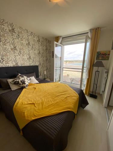 - une chambre avec un lit doté d'une couette jaune et d'une fenêtre dans l'établissement Un Balcon sur la Mer, à Crozon