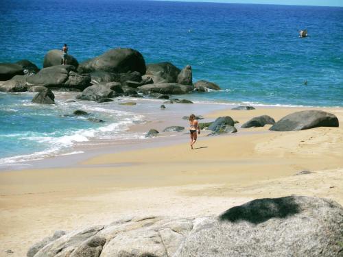 a woman walking on a beach near the ocean at Romantic Casa Rumi overlooking the Sea in Sayulita