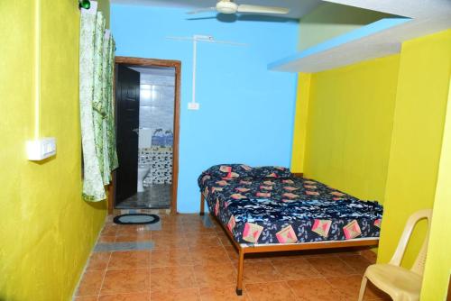 a bedroom with a bed in a room with yellow walls at Gajram Homestay Honnavar in Kāsarkod