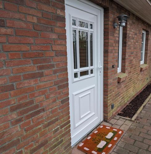 a white door on the side of a brick building at Hygge am See in Aventoft