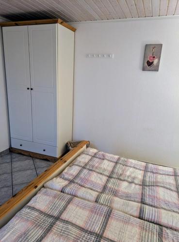 a bedroom with a bed and a cabinet at Hygge am See in Aventoft