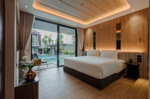 a bedroom with a large bed and a large window at Richmann Resort Hotel Hatyai in Hat Yai