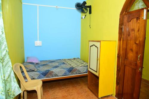 a small bedroom with a bed and a chair at Gajram Homestay Honnavar in Kāsarkod