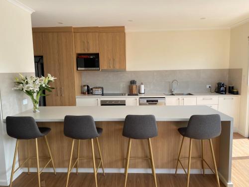 a kitchen with a counter and four stools at Seaview on Terry Court in Kingscote