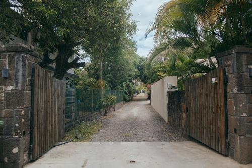 an alley with a fence and palm trees on a street at Barachois Cabana in Tamarin