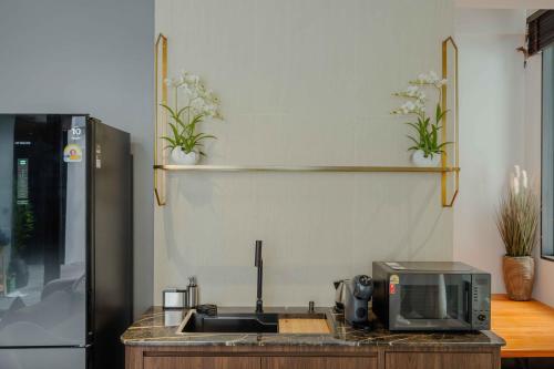 a kitchen with a sink and a microwave at Richmann Resort Hotel Hatyai in Hat Yai