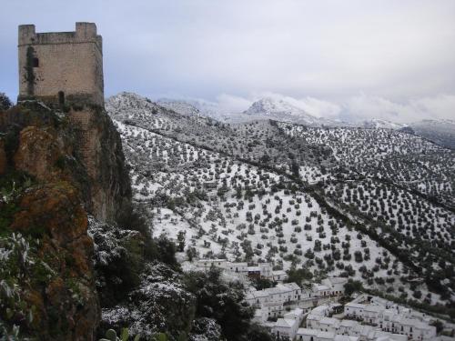a castle on the side of a mountain with snow at Casa El Villa in Zahara de la Sierra