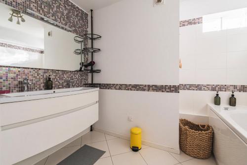 La salle de bains blanche est pourvue d'un lavabo et d'une baignoire. dans l'établissement La Parenthèse - spacieux 3 chambres - centre ville, à Reims