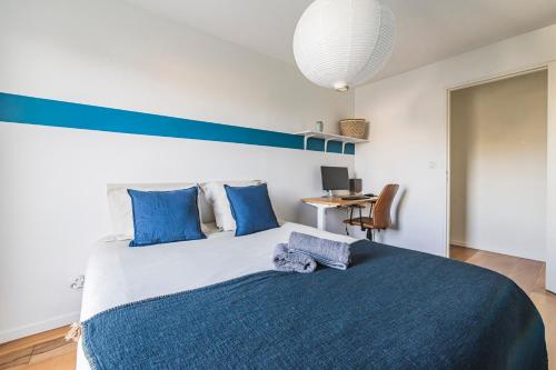 - une chambre avec un lit doté d'oreillers bleus et d'un bureau dans l'établissement La Parenthèse - spacieux 3 chambres - centre ville, à Reims
