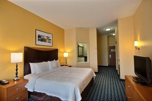 a hotel room with a bed and a flat screen tv at Fairfield Inn & Suites by Marriott Milwaukee Airport in Oak Creek