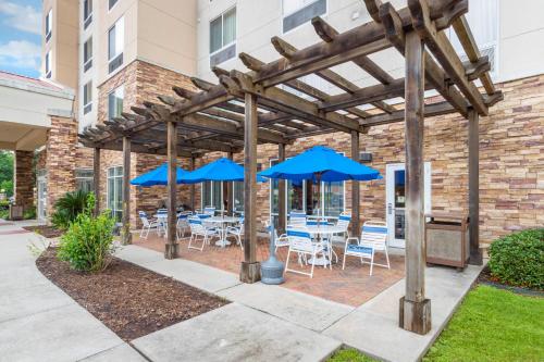 a patio with blue umbrellas and tables and chairs at Fairfield Inn & Suites by Marriott Houston Conroe in Conroe