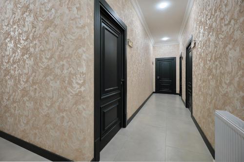 an empty corridor with black doors and tiled walls at Samarkand Hostel in Samarkand
