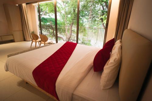 a bed with a red and white blanket and a window at RIVERSCAPES by NOORJEHAN in Palakkad