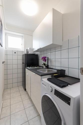 a white kitchen with a sink and a washing machine at R APARTMENTS BUDAPEST in Budapest