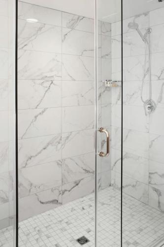 a shower with white marble walls and a glass door at Delta Hotels by Marriott Burnaby Conference Centre in Burnaby