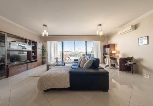 a large bedroom with a blue couch and a television at Jacuzzi Terrace Getaway with Valletta Views in Sliema