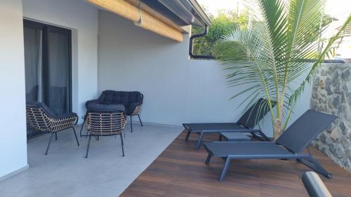 a patio with chairs and tables and a plant at Villa standing 50 in Ravine des Cabris