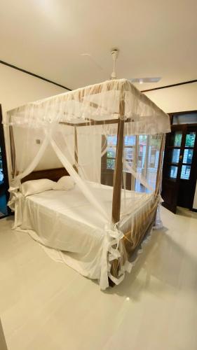 a bedroom with a canopy bed with white sheets at Hasi Villa in Ahangama