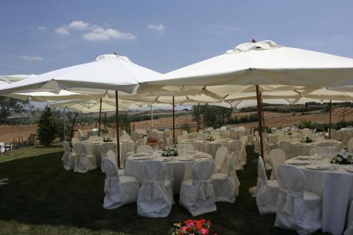 a group of tables and chairs under white umbrellas at Agriturismo Il Macchione in Pienza