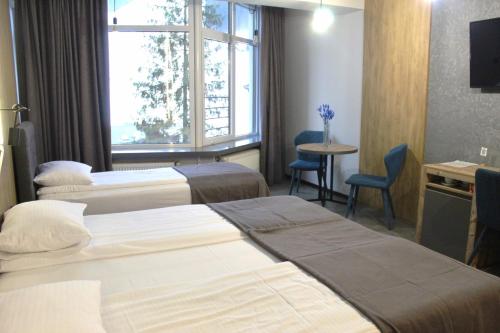 a hotel room with two beds and a table and a window at Синя гора in Bukovel