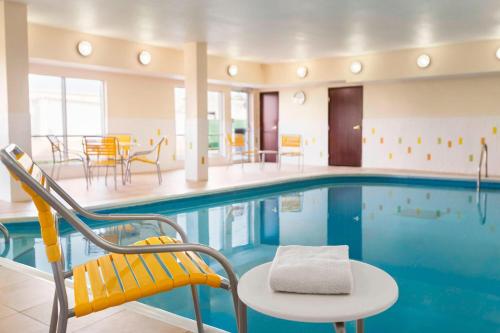 a pool with a chair and a table and chairs at Fairfield Inn & Suites by Marriott Mankato in Mankato