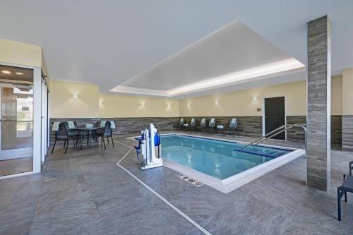 a pool in the middle of a room with tables and chairs at Fairfield Inn & Suites by Marriott Milwaukee Brookfield in Brookfield