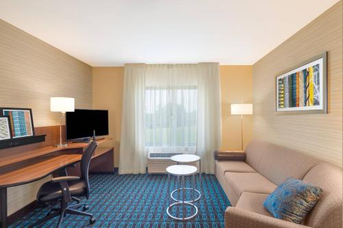 a hotel room with a couch and a desk with a computer at Fairfield Inn & Suites by Marriott Bloomsburg in Bloomsburg
