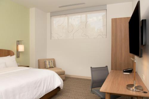 a hotel room with a bed and a desk and a television at Element Scottsdale at SkySong in Scottsdale