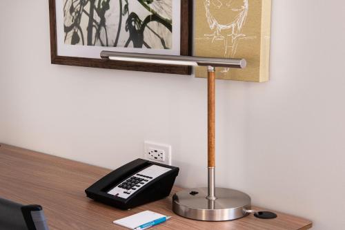 a desk with a phone on a table with a lamp at Element Scottsdale at SkySong in Scottsdale