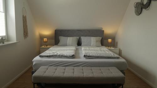 a bedroom with a large bed and a bench at Haus Nordseeliebe mit Außensauna, Outdoor Dusche und Wallbox in Dornum