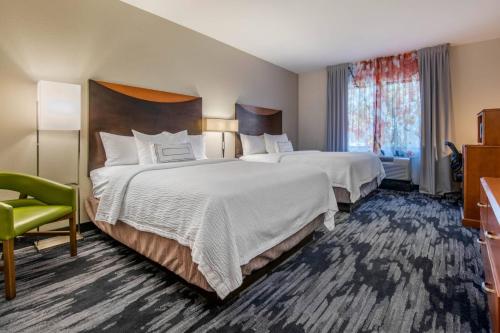 a hotel room with two beds and a green chair at Fairfield Inn and Suites Holiday Tarpon Springs in Holiday