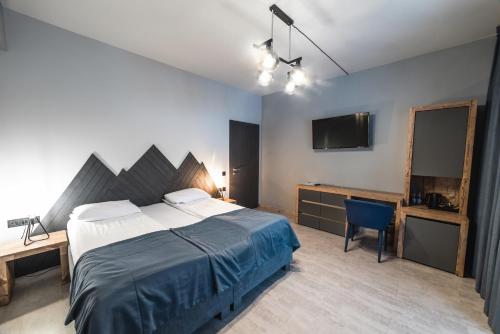 a bedroom with a bed and a desk and a television at Синя гора in Bukovel