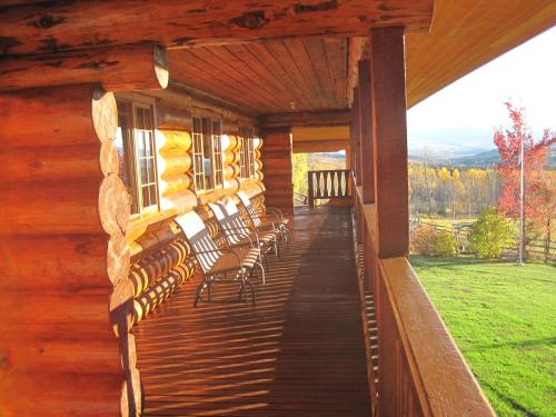 a porch of a log cabin with chairs on it at Smithers Driftwood Lodge in Smithers