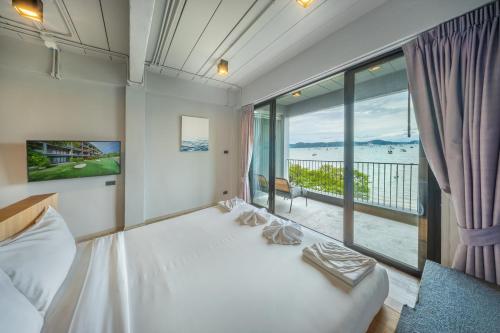 a bedroom with a white bed and a large window at SHIN Arch39 Phuket Beach Front - SHA Plus in Chalong 