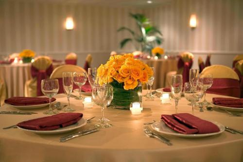 a table with wine glasses and a vase of orange flowers at Four Points by Sheraton Wakefield Boston Hotel & Conference Center in Wakefield