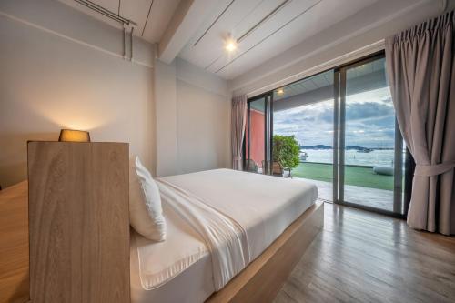a bedroom with a large bed and a large window at SHIN Arch39 Phuket Beach Front - SHA Plus in Chalong 