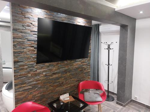 a living room with a tv on a brick wall at De Lux Apartment Maki in Banja Luka