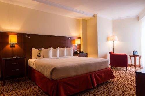 a hotel room with a large bed and a red chair at Marriott Venezuela Hotel Playa Grande in Playa Grande