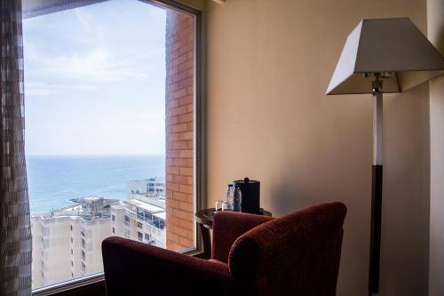 a room with a window with a chair and a lamp at Marriott Venezuela Hotel Playa Grande in Playa Grande