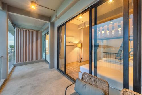 a room with a balcony with a bed and windows at SHIN Arch39 Phuket Beach Front - SHA Plus in Chalong 