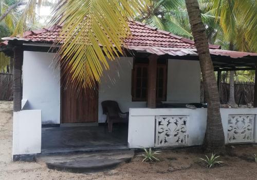 a small white house with a palm tree at Skykite Resort & Hostel Kalpitiya Sri Lanka in Kalpitiya