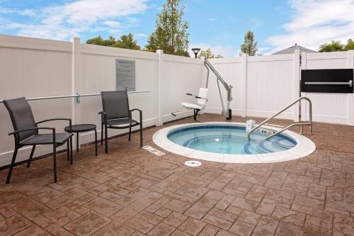 a patio with a hot tub with chairs and a table at Fairfield Inn & Suites by Marriott Queensbury Glens Falls/Lake George in Queensbury