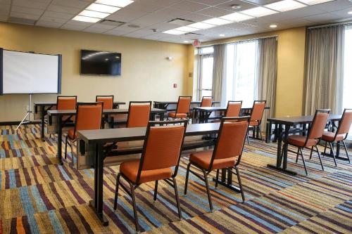a conference room with tables and chairs and a white screen at Fairfield Inn & Suites by Marriott Madison Verona in Verona