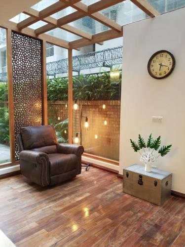 a living room with a chair and a clock on a wall at The Midori by Lakeshore, Gulshan , Dhaka in Dhaka
