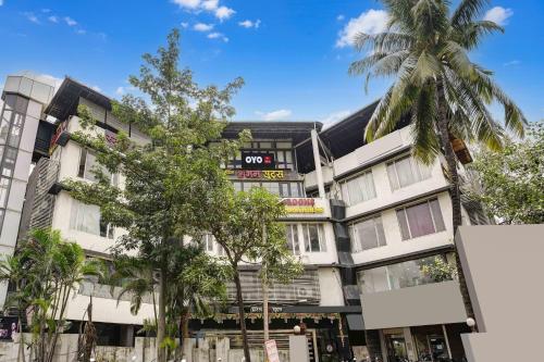 an apartment building with palm trees in front of it at Hotel O Shubham Suites in Dive
