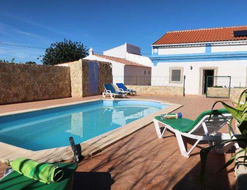 a swimming pool with two chairs and a house at Ferienhaus Casa Limoeiro by fewo-plan ESTO101 an der Algarve in Azinheiro