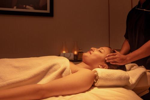 a woman laying on a bed getting a massage at Four Points by Sheraton Kochi Infopark in Cochin
