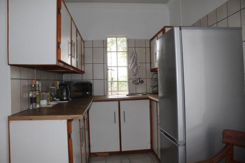 a kitchen with white cabinets and a stainless steel refrigerator at Angel Cottage in Tzaneen