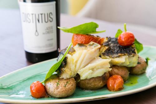 a plate of food with meatballs and vegetables and a bottle of wine at Four Points by Sheraton Sesimbra in Sesimbra