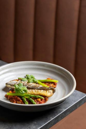 two pieces of fish on a plate with broccoli at Four Points by Sheraton Edinburgh in Edinburgh